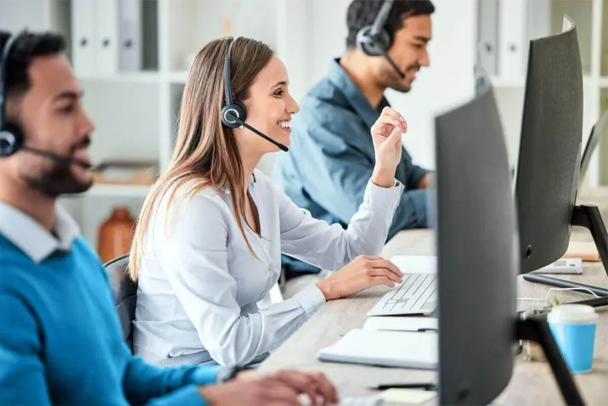 Customer support agents wearing headsets helping players at computer desks