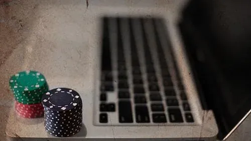 Stacked casino poker chips sitting beside an open laptop keyboard