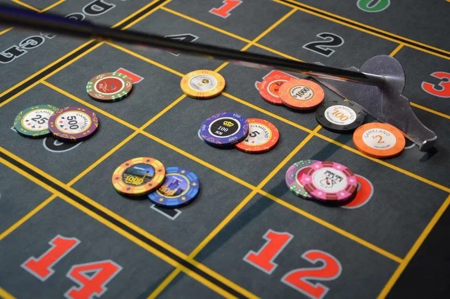 Close-up of casino chips of varying denominations stacked on a roulette table layout