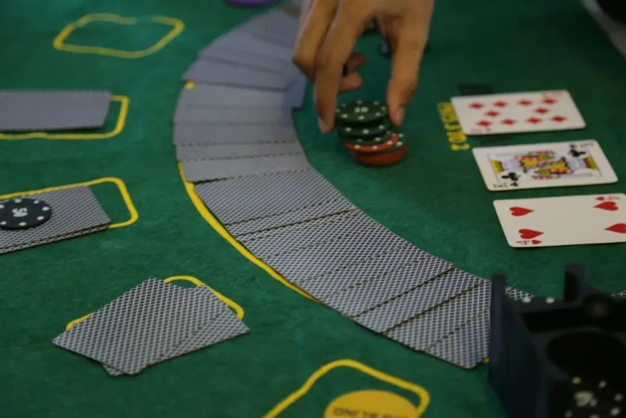 A casino photo showing cards fanned out and a hand placing betting chips at baccarat