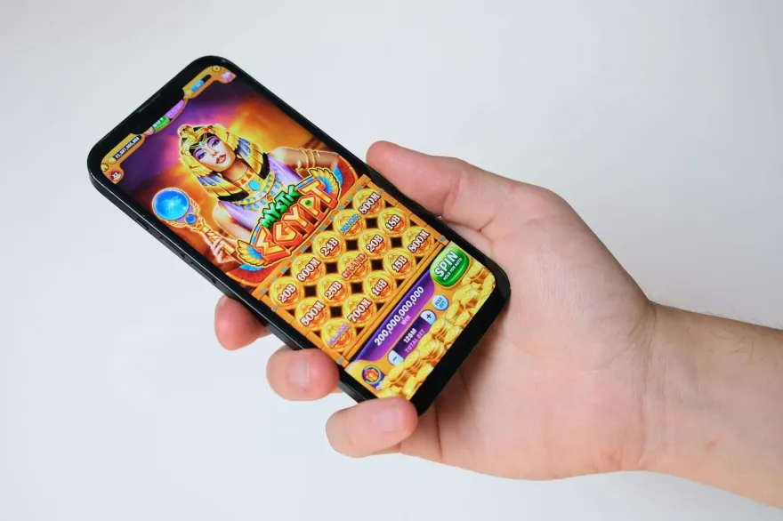 Hand holding a phone displaying an Egyptian themed jackpot slot game