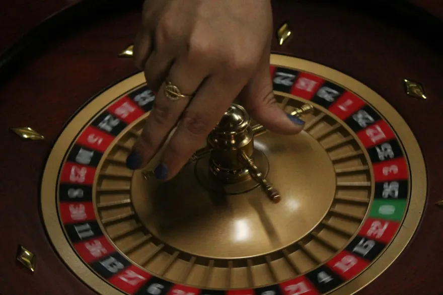 Close up of a hand spinning a golden casino roulette wheel