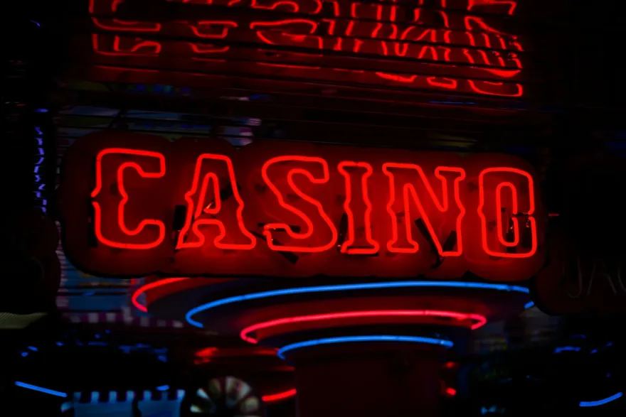 Red neon casino sign glowing above a gaming floor at night