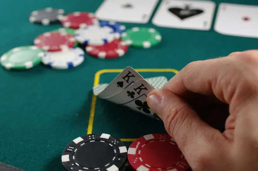 Player's hidden pocket kings poker hand beside stacked casino chips