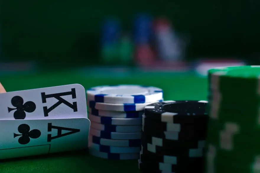Poker hole cards next to stacked blue, black and green chips