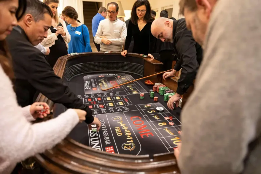 Group of players betting around a craps game with a dice stick
