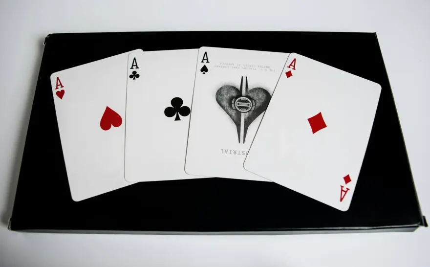 Four ace playing cards fanned out on a black case
