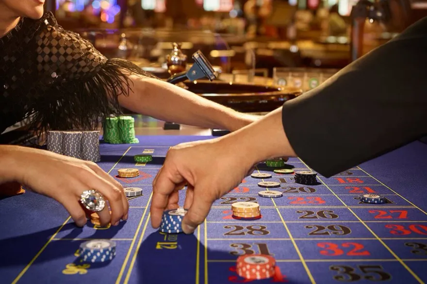 Two players placing casino chips on a roulette table