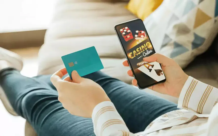 Person holding a bank card and smartphone showing a mobile casino app