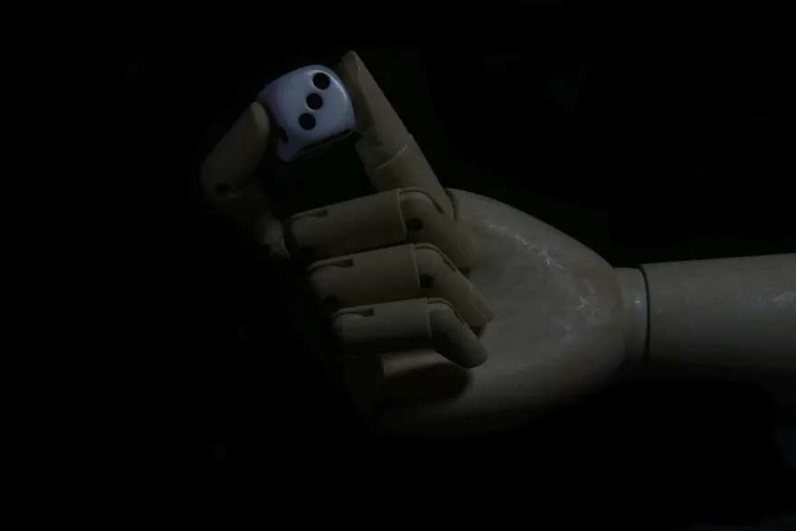 Artistic wooden hand holding a single white casino die