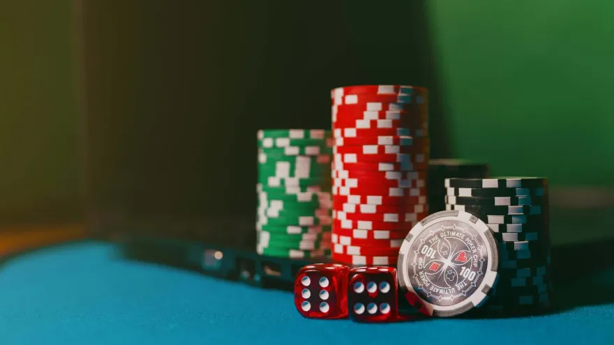 Stacks of casino chips and red dice on blue felt